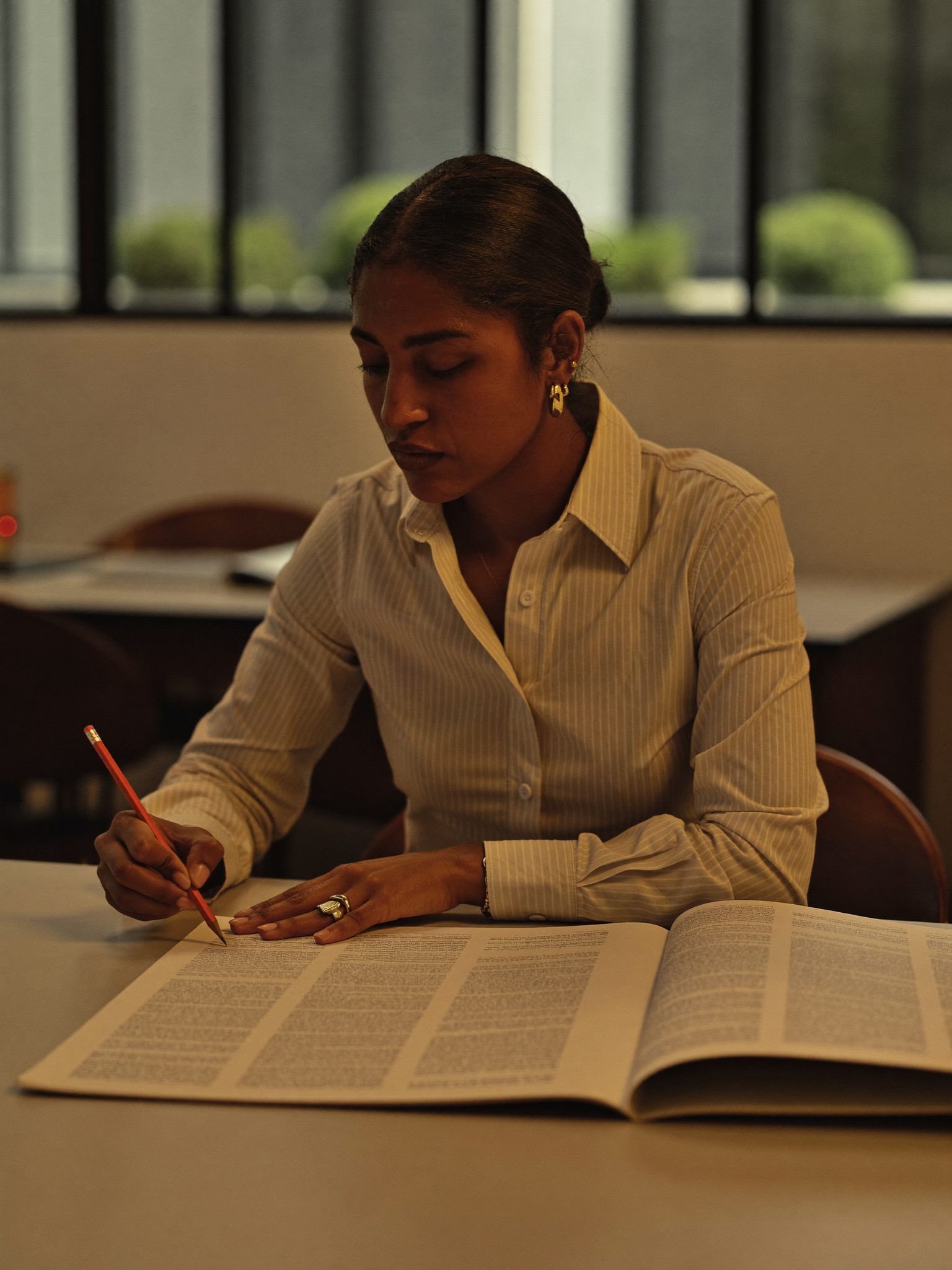 An editor reviewing proof pages with a pencil in hand